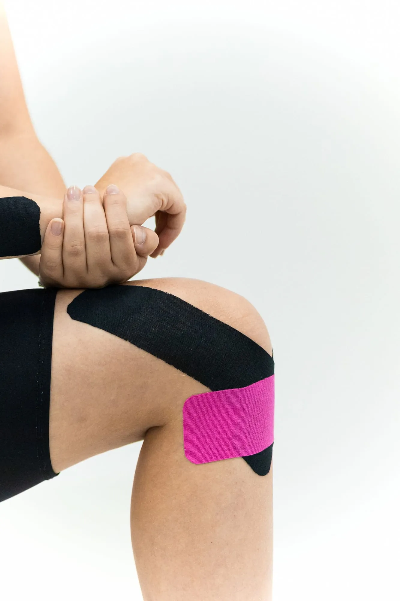 Knie mit schwarzem und pinkem Tape vor weißem Hintergrund